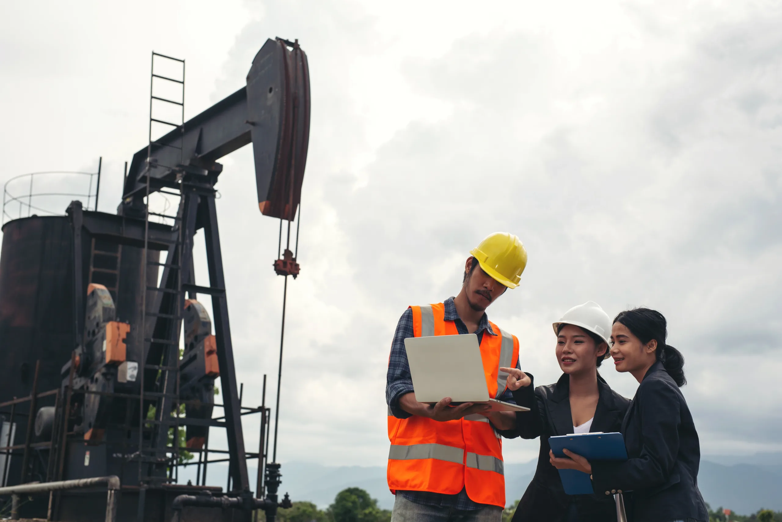 engineering-team-stands-beside-working-oil-pumps-with-sky